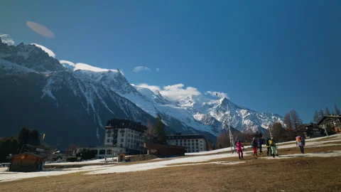 Skiers walking through Chamonix town with dramatic Mont Blanc massif rising Video stock 333986508