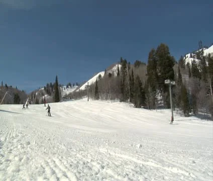 Skiiers glide down hill on blue sky day Stock Footage 21671885