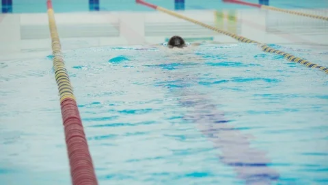 Skill swimmer hardly working out in indoor pool swimming across track. Stock Footage 116661946