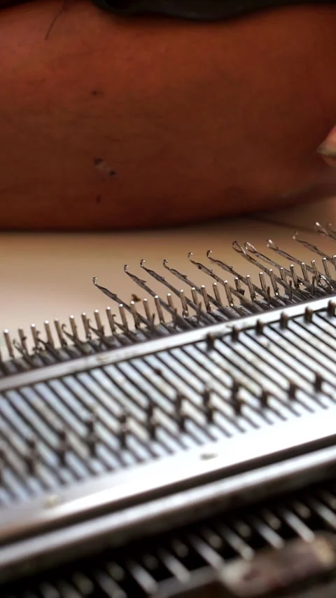 A skilled artisan utilizes a traditional hand knitting machine Видео 338054577