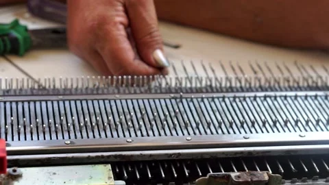 A skilled artisan utilizes a traditional hand knitting machine Видео 338054635