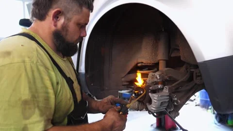 Skilled automotive technician using a torch to heat a component during car Vidéo 333176160
