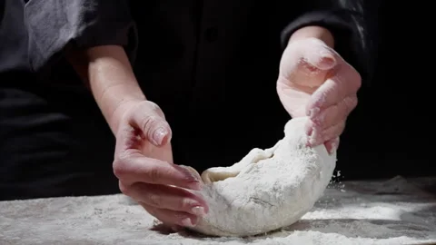 Skilled baker kneading artisan bread dough with experienced hands, working on Stock Footage 301644660