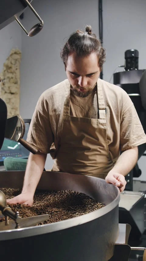 Skilled barista roasts coffee beans in a modern roasting facility during a busy Stock Footage 321765901