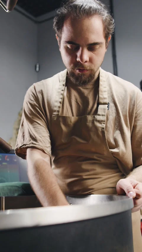 Skilled barista roasts coffee beans in a modern roasting facility during a busy Stock Footage 321765939