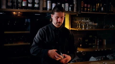 Skilled bartender in a dimly lit bar preparing a cocktail with stainless steel Video stock 318655638