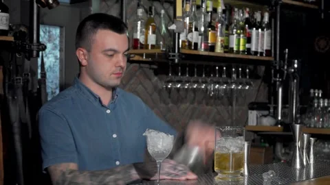 Skilled bartender expertly crafting a vibrant cocktail at the bar Stock Footage 311655323