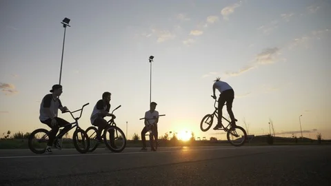 Skilled biker guy entertaining his friends doing rotation jump on his bicycle Stock Footage 86369532