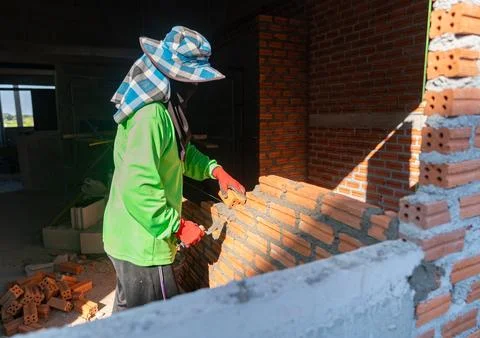 Skilled bricklayer constructing a brick wall with mortar and trowel. Stock Photos