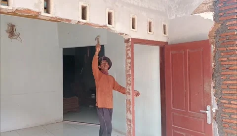 Skilled builder demolishing a concrete wall with a hammer for home remodeling. 動画素材 335019124