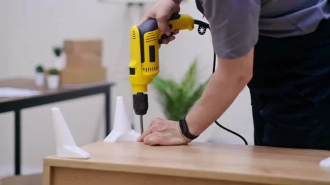 Skilled carpenter in blue overalls, using yellow electrical drill screwdriver Stock Footage 238029858