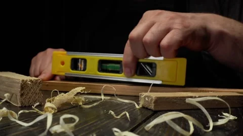 Skilled carpenter uses a level tool to ensure accuracy while measuring wooden Stock Footage 333649459