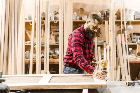 Skilled carpenter using a router to craft wooden panels in a well-equipped Stock Photos