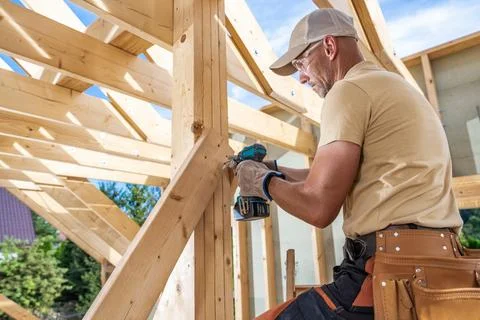 Skilled Carpenter at Work Constructing a Wooden Roof Frame in a Residential.. Foto stock