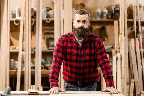 Skilled carpenter working in a well-equipped workshop surrounded by wood Stock Photos
