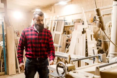 Skilled carpenter working in a workshop surrounded by wood and tools during the Stock Photos