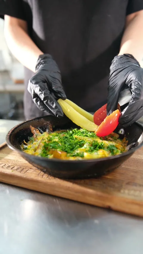 Skilled chef in black gloves carefully garnishing a freshly cooked pan-fried Video stock 318317105