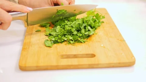 Skilled chef chops vibrant greens on wooden cutting board. Precise movements Stock Footage 271703240