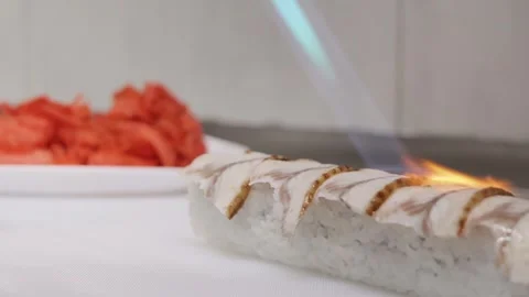 A skilled chef expertly prepares grilled fish sushi, placing it delicately with Stock Footage 304456623