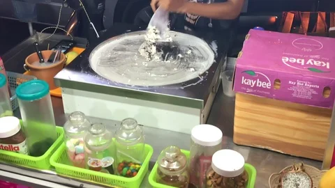 A skilled chef making a modern ice cream roll in a vendor cart in Bangkok Stock Footage 125523738