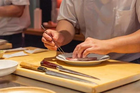 Skilled chef preparing sushi with precision on wooden cutting board Stock Photos