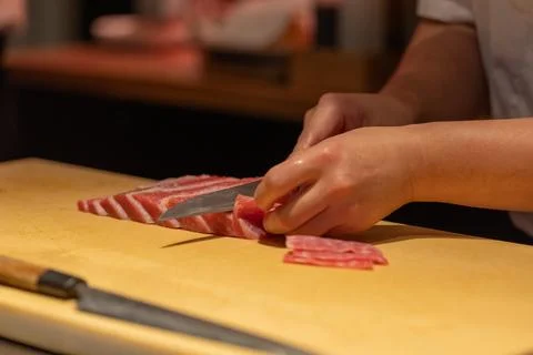 Skilled chef slicing fresh fish on wooden cutting board in kitchen Stock Photos