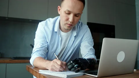 Skilled company manager guy with bio hand prothesis writes Stock Footage 157349876