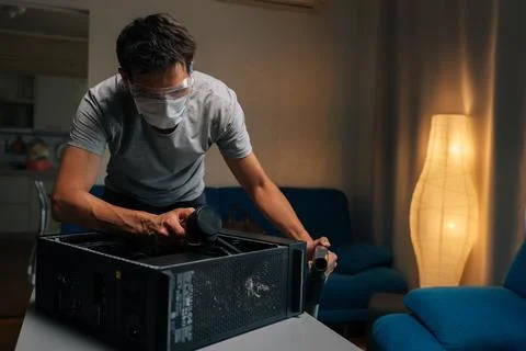 Skilled computer technician wearing protective gear cleaning internal components Stock Photos