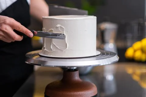 Skilled confectioner making pattern on white mastic with knife on blurred Stock Photos