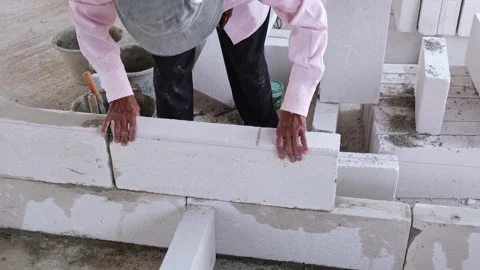 A skilled construction worker is assembling lightweight concrete bricks int.. Stock Footage 300075801