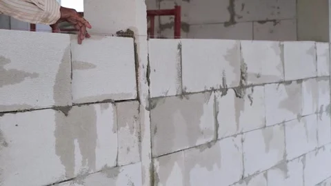 A skilled construction worker is building lightweight concrete bricks into .. Stock Footage 300075800