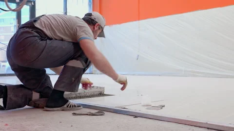 Skilled construction worker lays white tile on new floor Video stock 146679736