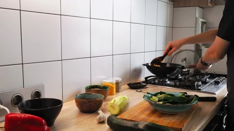 A skilled cook prepares a vibrant vegetable stir-fry using fresh produce on a Stock Footage 316479657