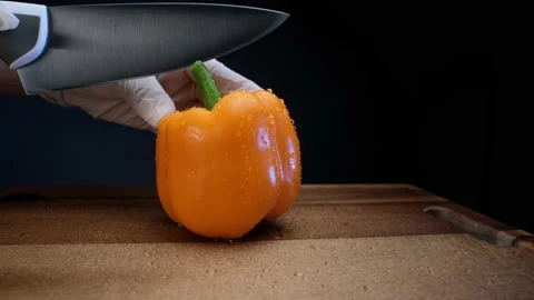 Skilled cook in white gloves cuts wet pepper with knife Видео 147016212