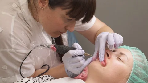 Skilled cosmetologist applying permanent make-up on lips in a beauty salon. Top Stock Footage 113497637