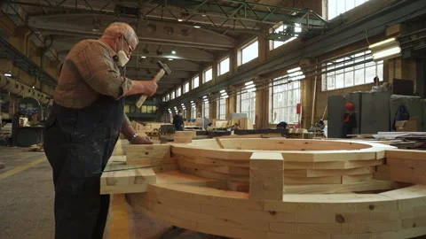 A skilled craftsman is diligently working on a large wooden structure inside his Video stock 281711135