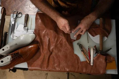 Skilled craftsman sewing leather with tools on a worktable, shoemaking in Stock Photos