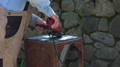 Skilled Craftsman Using an Angle Grinder on a Metal Sheet in a Workshop Stock Footage 337427526