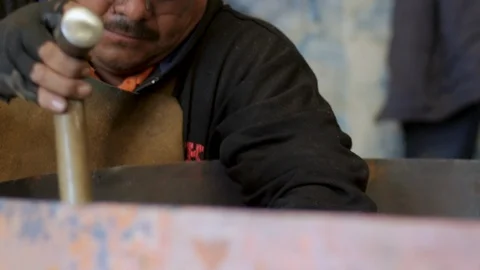 Skilled craftsman using a hammer on a large copper sheet in slow motion Stock Footage 98843813