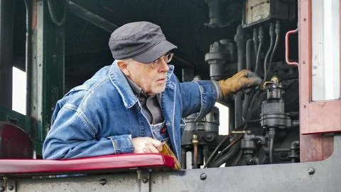 Skilled engineer works on steam engine controls at a historic railway stati.. Stock Photos