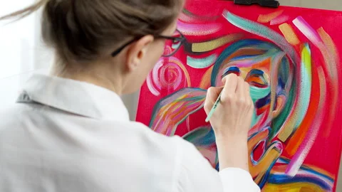 Skilled female painter creating expressive artwork on easel in bright studio.  Vídeos de archivo 331146024