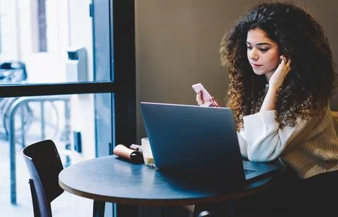 Skilled freelancer with smartphone reading text publication browsed on netbook Stock Photos