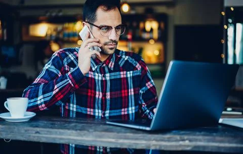 Skilled freelancer in spectacles making booking Stock Photos