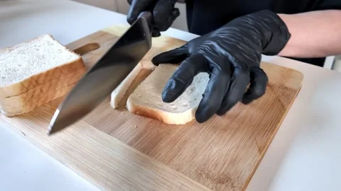 Skilled gloved hands carefully slice fresh white bread on a rustic wooden c.. Stock Footage 318411026