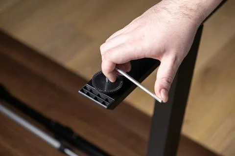 Skilled hand precisely using an Allen wrench to securely fasten a black fur.. Stock Photos