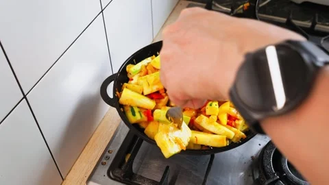Skilled hands skillfully stir-fry a vibrant mix of vegetables, creating a 動画素材 316483899
