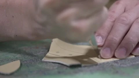 Skilled hands trimming a small leather piece with a sharp blade on a cutting Stock Footage 340277476