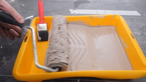 Skilled handyman moves roller brush in special yellow tray Stock Footage 125008876