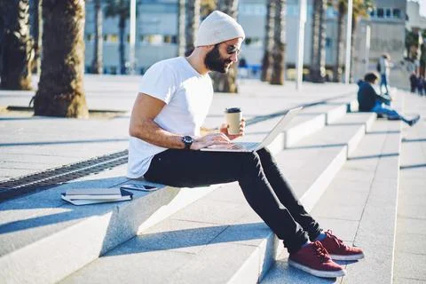 Skilled hipster guy reading web publication while networking social media Stock Photos
