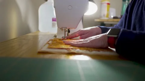 Skilled homemaker sewing quilt block scraps together on a machine - ORANGE Stock Footage 167627554